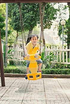 Joyful boy in elementary school age riding toy on children`s playground