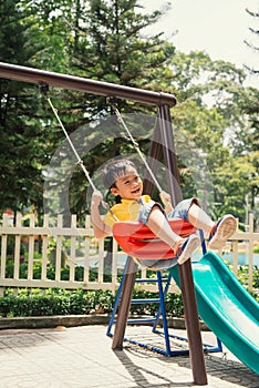 Joyful boy in elementary school age riding toy on children`s playground