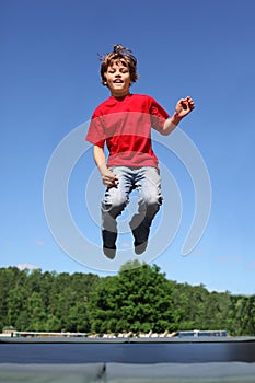 Joyful boy jumps on trampoline