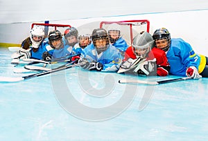 Joyful boys and girls laying on ice hockey rink