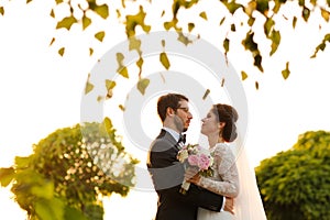 Joyful bride and groom with bouquet embracing