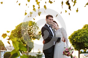 Joyful bride and groom with bouquet embracing