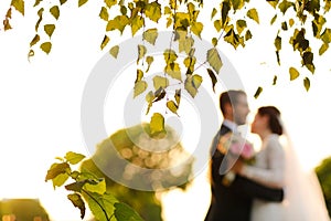 Joyful bride and groom with bouquet embracing