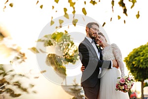 Joyful bride and groom with bouquet embracing