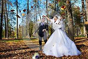 Joyful bride and groom iand falling leaves