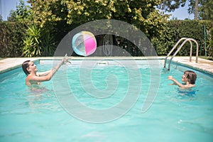 Joyful brothers playing ball in swimming pool