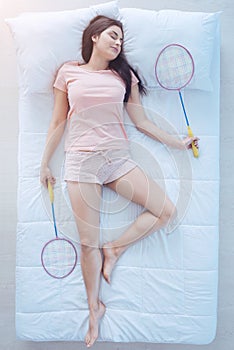 Joyful brunette sleeping with badminton rackets