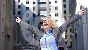 Joyful business lady showing yes gesture raising hands up, goal achievement