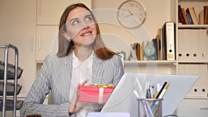 Joyful business woman with gift box in modern office