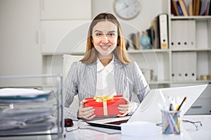 Joyful business woman with gift box in office
