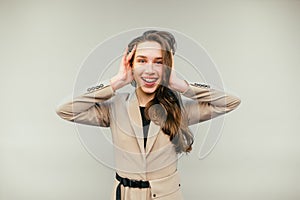 Joyful business woman in a jacket stands on a beige background and looks at the camera with a happy face