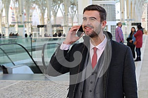 Joyful businessman calling by phone from train station