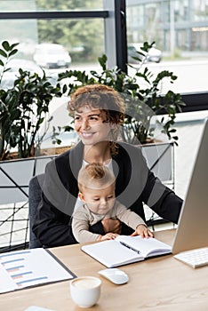 joyful businesswoman looking away while sitting