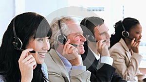 Joyful call centre agents sitting while wearing headsets