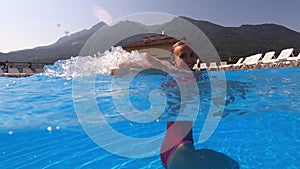 Joyful and carefree vacationer girl splashing water in the pool