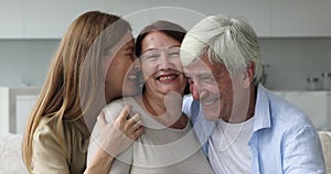 Joyful caring adult daughter hugging old mature parents with love