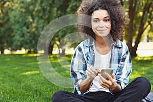 Cheerful young woman using laptop in park