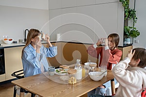Joyful caucasian family young mother and two kids having fun during breakfast at home