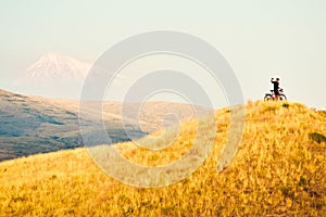 joyful caucasian male cyclist standing by touring bicycle looking to camera on top hilltop happy after reaching goals Stand