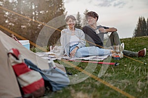 Joyful Caucasian man and woman in love resting at tent at nature. Hikers camping in mountains.