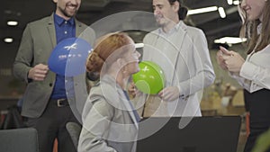 Joyful caucasian office workers congratulating their colleague with birthday. Positive coworkers partying in open space