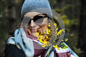 Joyful caucasian woman with colorful maple leaf in autumn nature