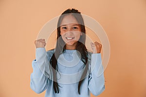 Joyful, celebrating success. Cute young girl is in the studio against background