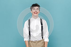 Joyful cheerful man wearing shirt and suspender, expressing positive emotions, being in good mood.