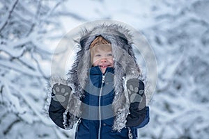 Joyful child Having Fun in Winter Park. Cute child in Winter park trees covered with snow. Well dressed enjoying the