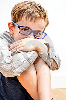 Joyful child hiding giggle in knees and hands for shyness