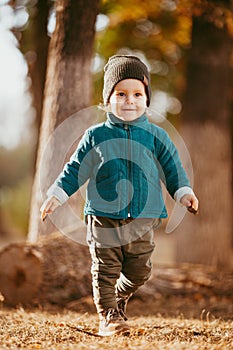 Joyful child runs. A boy dressed in a green jacket and brown pants.