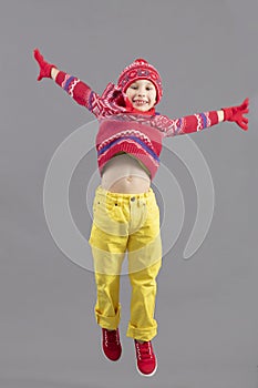The joyful Child in warm bright clothes bounces. photo