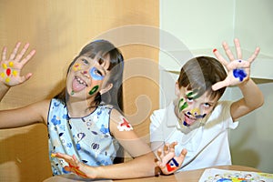 Joyful children with paints on their faces. Children paints faces with colors.