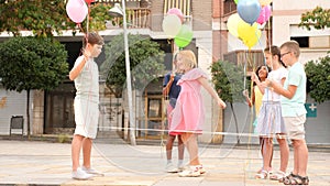 Joyful children playing with balloons and jumping rope outdoors.