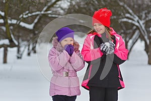 Joyful children playing in snow. Two happy girls having fun outside winter day