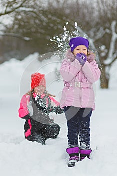 Joyful children playing in snow. Two happy girls having fun outside winter day