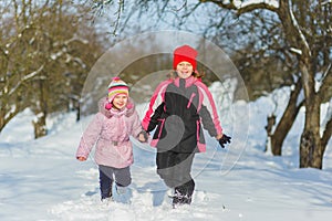 Joyful children playing in snow. Two happy girls having fun outside winter day