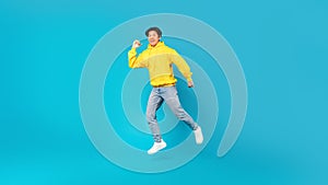 Joyful Chinese Teen Boy Jumping Smiling Posing Over Blue Background