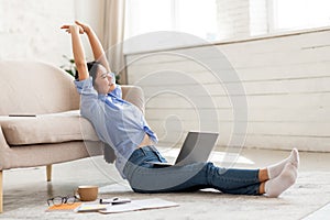 Joyful chinese woman stretching while using laptop