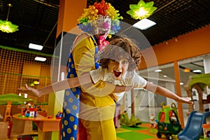 Joyful clown and kid feeling excitement playing game together at daycare center