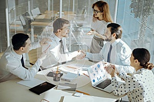 Joyful colleagues giving handshake having solved conflict