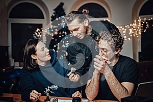 Joyful company of three students sits at table researching a fossil