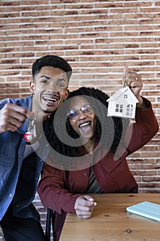Joyful couple celebrating buying new home showing keys and looking at camera. Happy man and woman smiling and holding