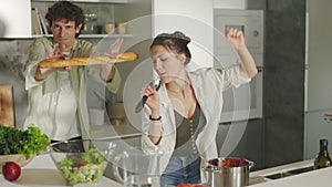 Joyful couple dancing and singing on modern kitchen