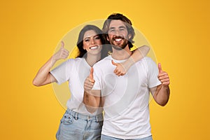 Joyful couple giving thumbs up and embracing, showcasing approval and happiness with bright smiles