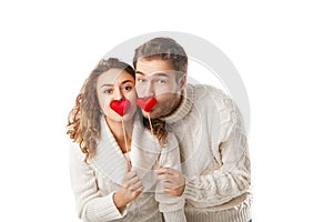 Joyful couple holding red hearts and laughing