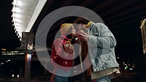 Joyful couple kissing on urban street. Man and woman enjoying snack food.