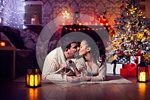 Joyful couple near christmas tree and fireplace in romantic lighting