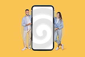 Joyful couple presenting giant smartphone for your design