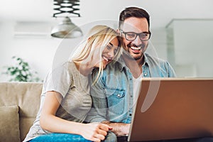 Joyful couple relax and work on laptop computer at modern living room